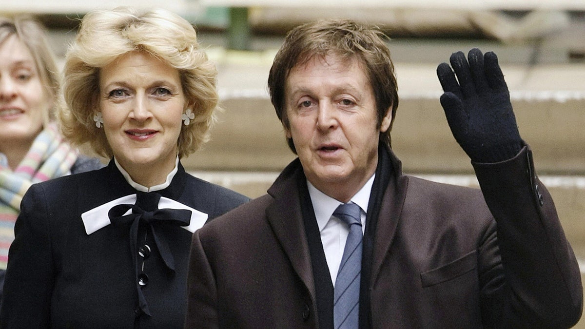 Fiona Shackleton standing next to Paul McCartney who is waving to a crowd.