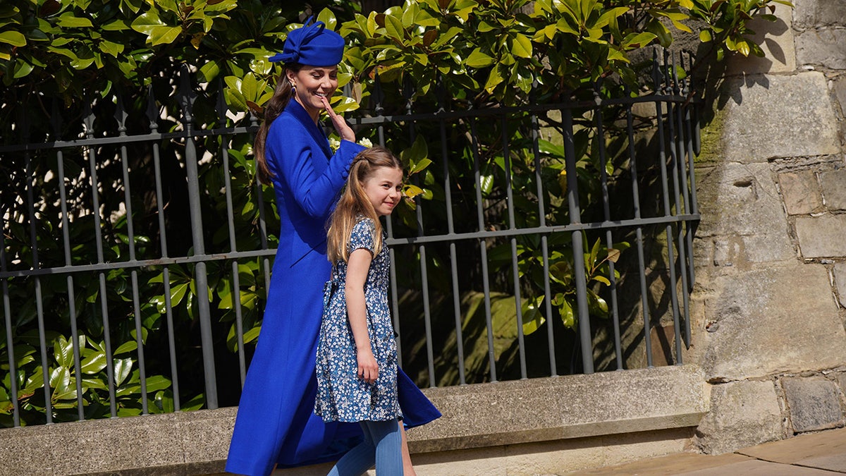 Kate Middleton walking with her daughter Princess Charlotte and waving.