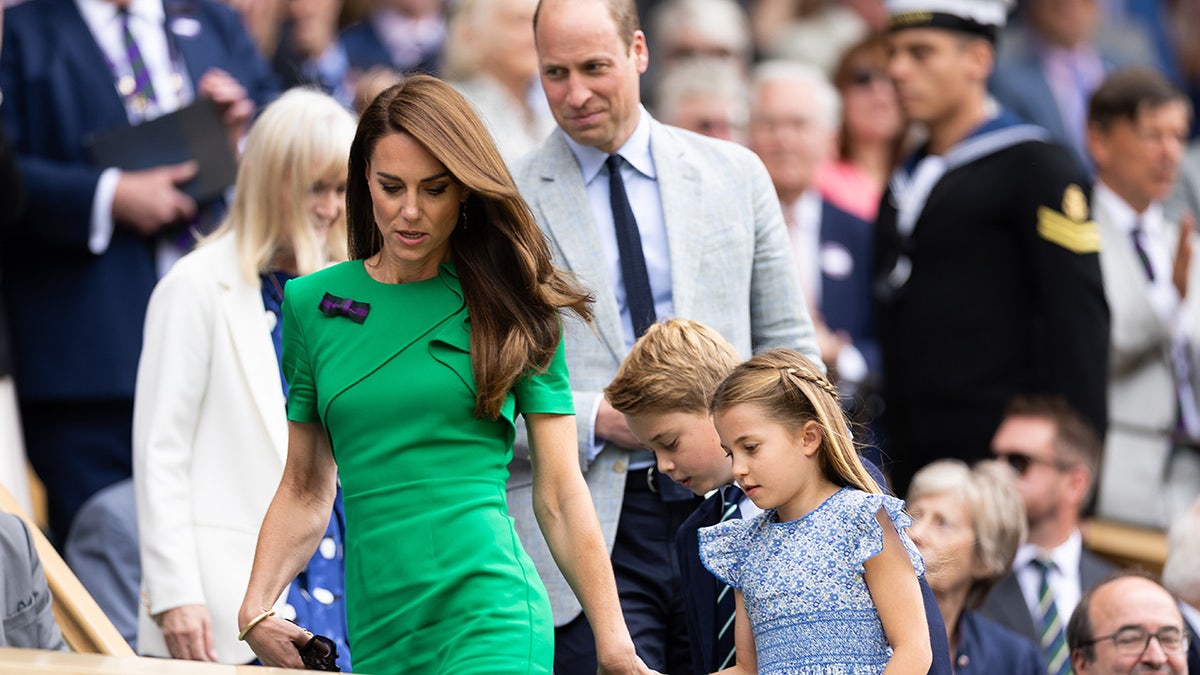 Kate Middleton liderando seus filhos no meio de uma multidão com o Príncipe William seguindo atrás