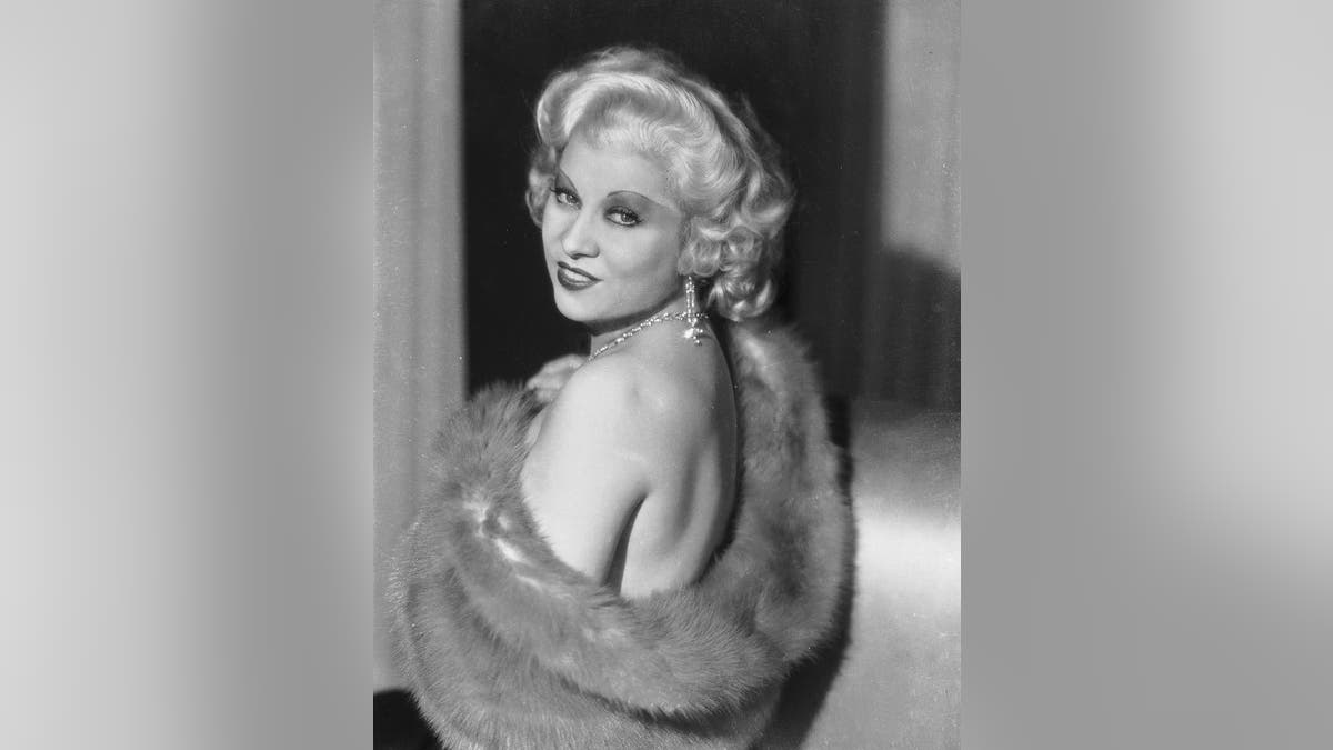 Mae West olhando por cima do ombro em uma foto vintage e glamorosa.