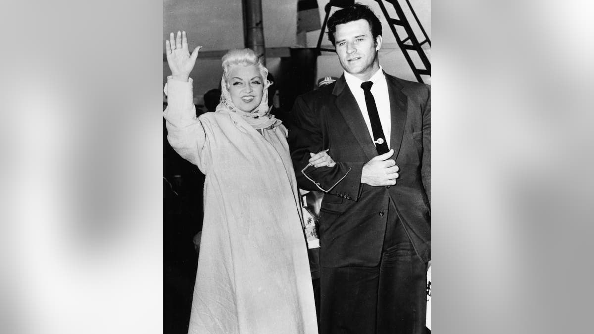 Mae West saludando del brazo de Chuck Krauser.