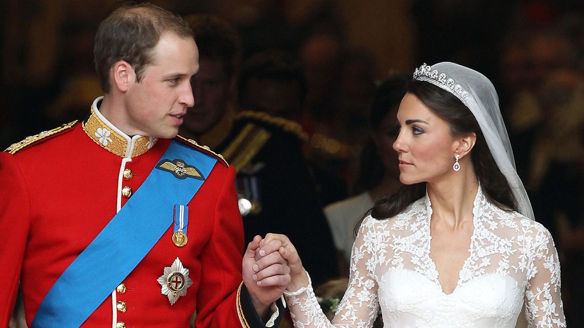 Prince William and Kate Middleton holding hands and looking at each other on their wedding day.