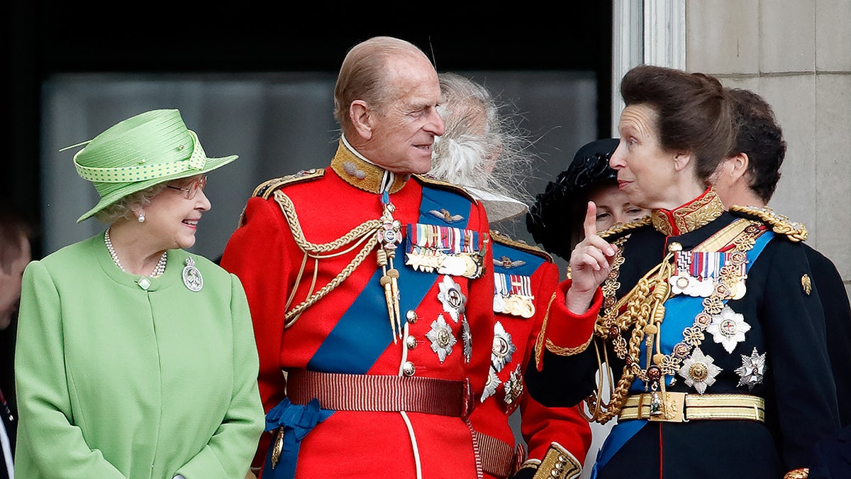 Princess Anne speaking to a smiling Prince Philip and Queen Elizabeth II
