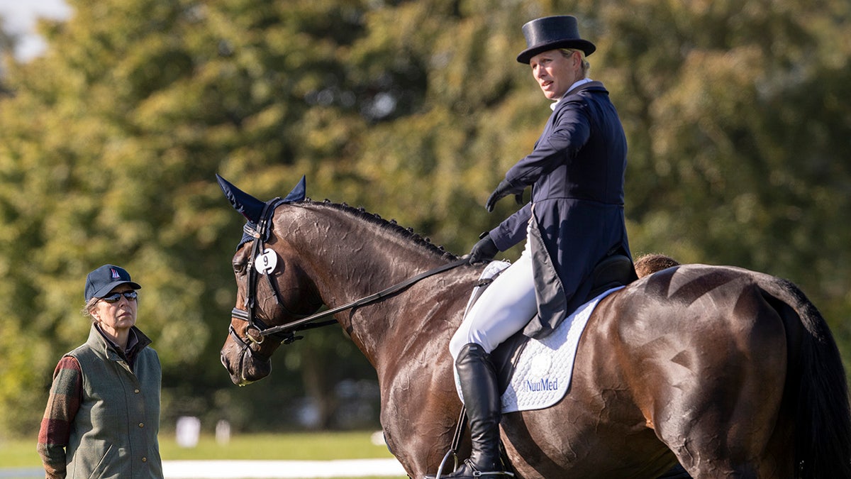 Zara Tindall riding a horse as Princess Anne looks on.