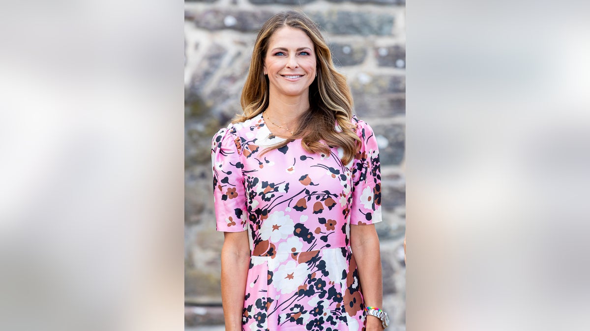 Princess Madeleine of Sweden wearing a pink floral dress and smiling.