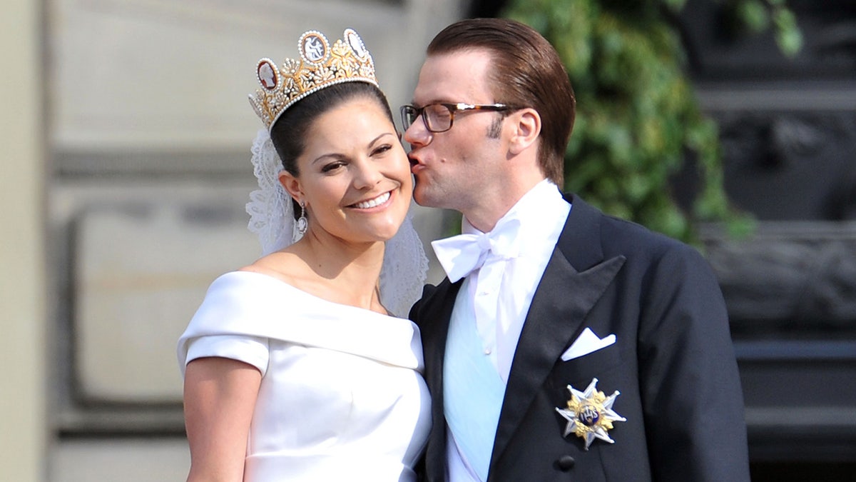 Princess Victoria smiling as she receives a kiss from her groom on their wedding day.