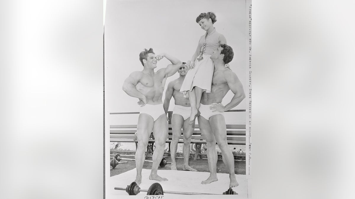 Vários homens musculosos admirando Debbie Reynolds.
