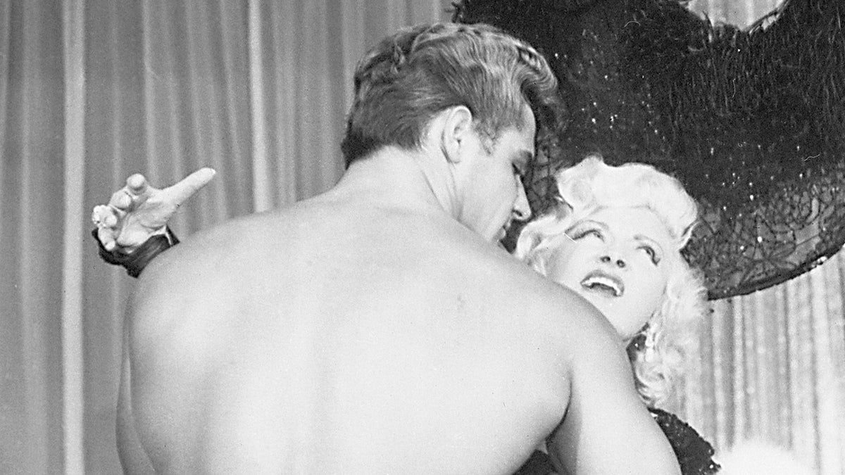 Richard DuBois embracing Mae West as she looks up in pleasure.