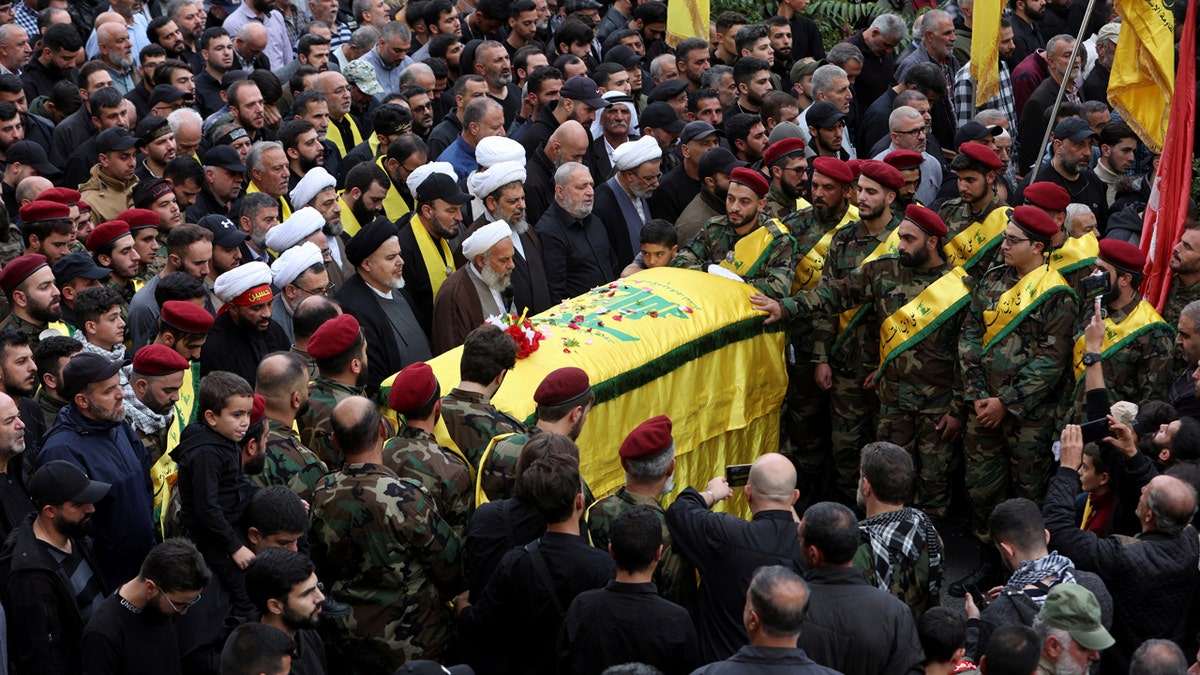 Mourners gathered near the coffin of Hezbollah member Jaafar Serhan, which was draped in a yellow flag.