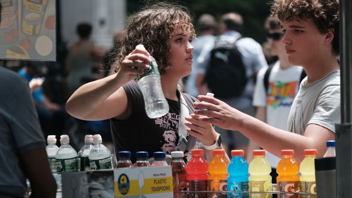 A woman buys a bottle aof water to coll down in the heat in New York City