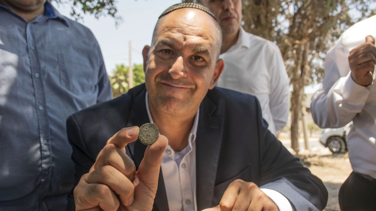 Hombre judío sosteniendo una moneda antigua