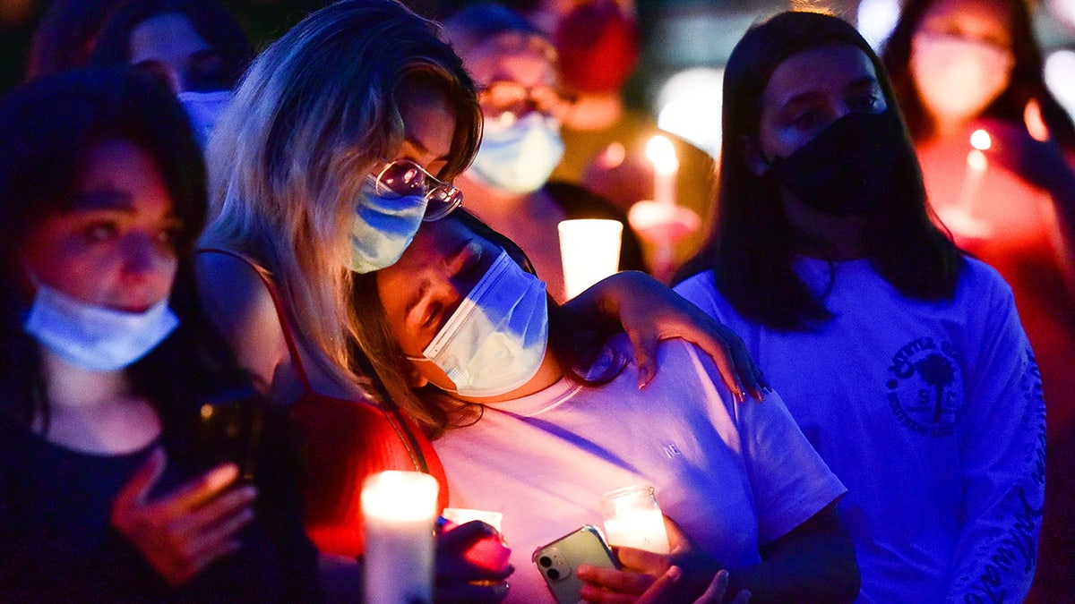 Mourners in face masks with lit candles.