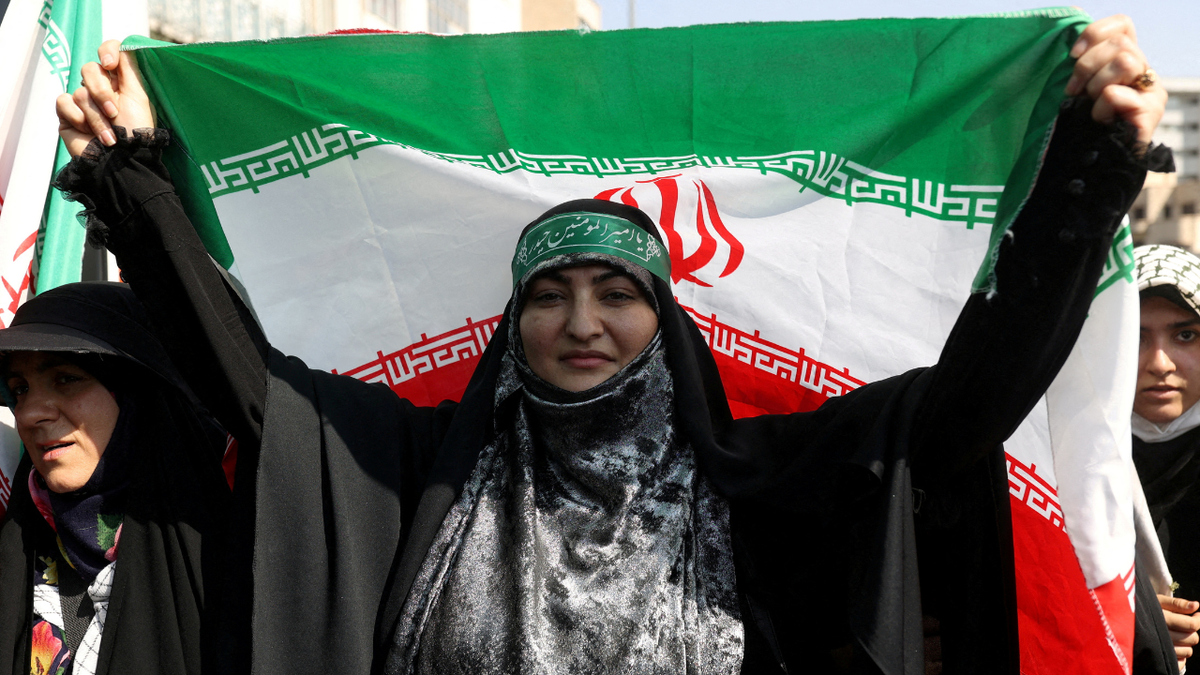 ایک ایرانی حکومت نواز خاتون ایرانی پرچم تھامے ہوئے ہے۔