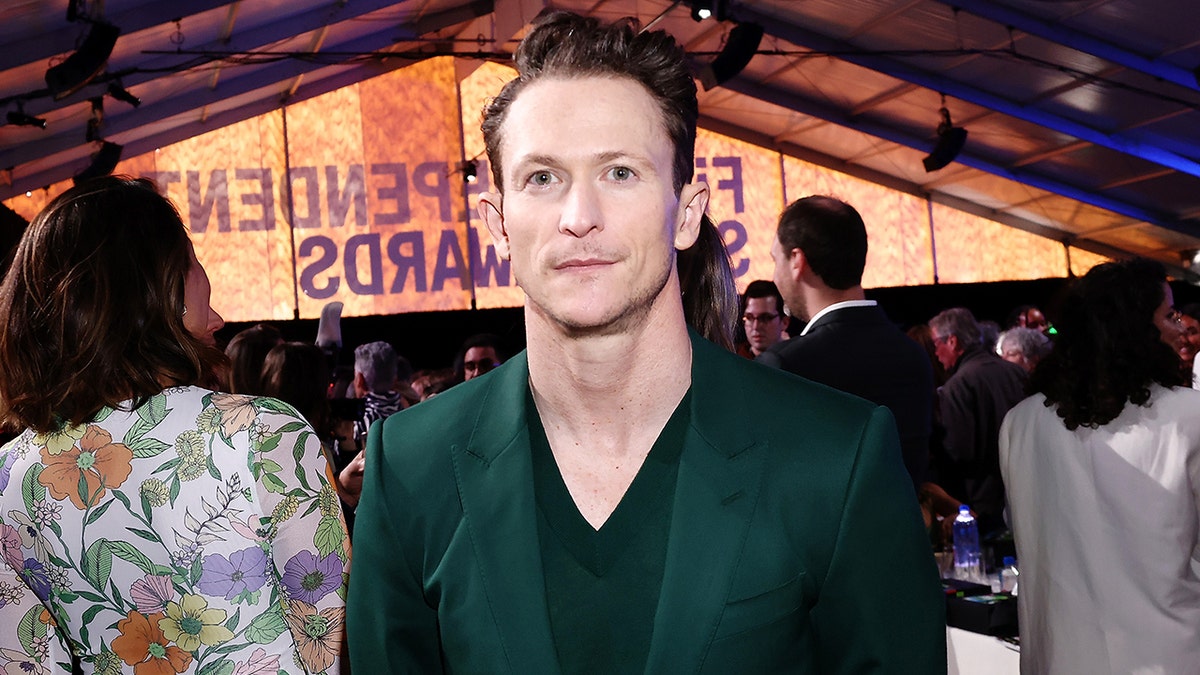 Jonathan Tucker wears a green suit