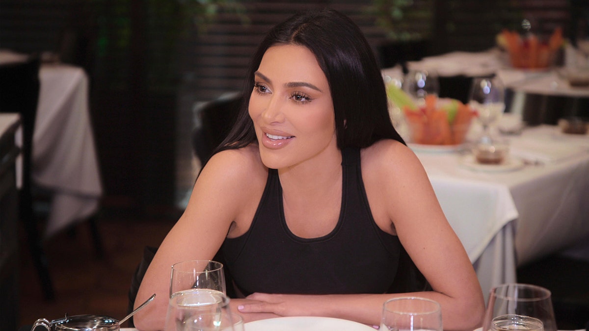 Kim Kardashian leaning on a table at a restaurant.