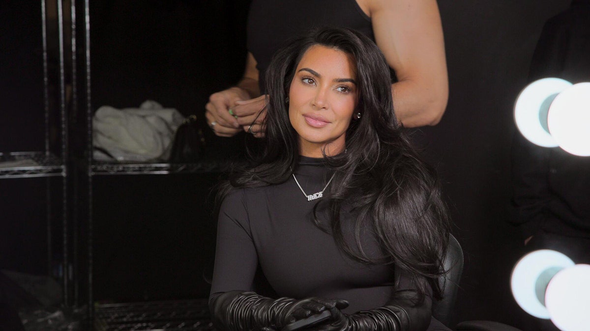 Kim Kardashian sitting in front of a vanity in all black