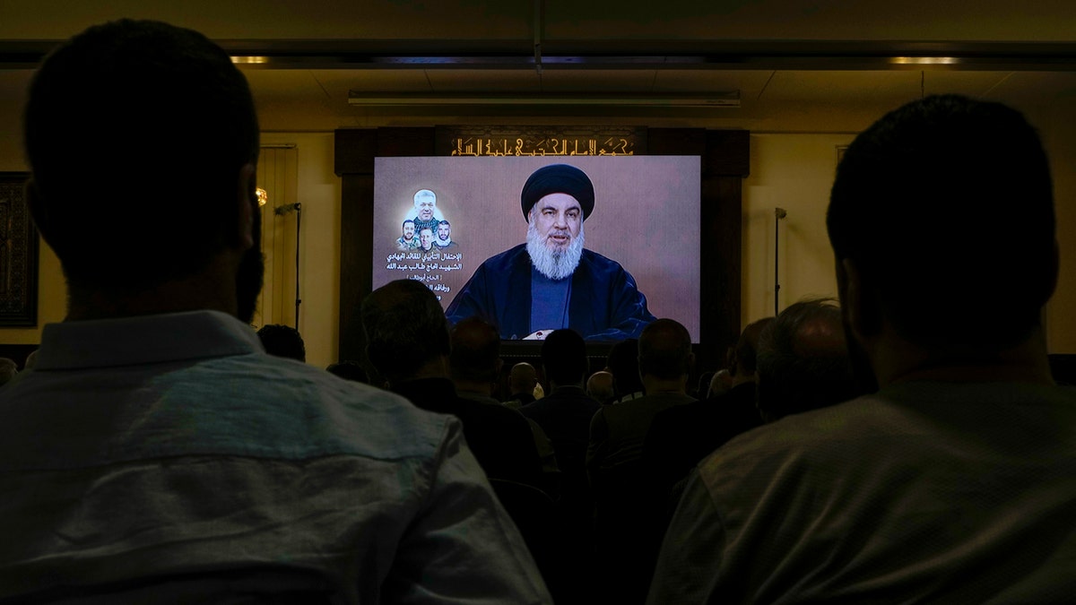 Hezbollah supporters watch a speech given by Hezbollah leader Sayyed Hassan Nasrallah on a screen.