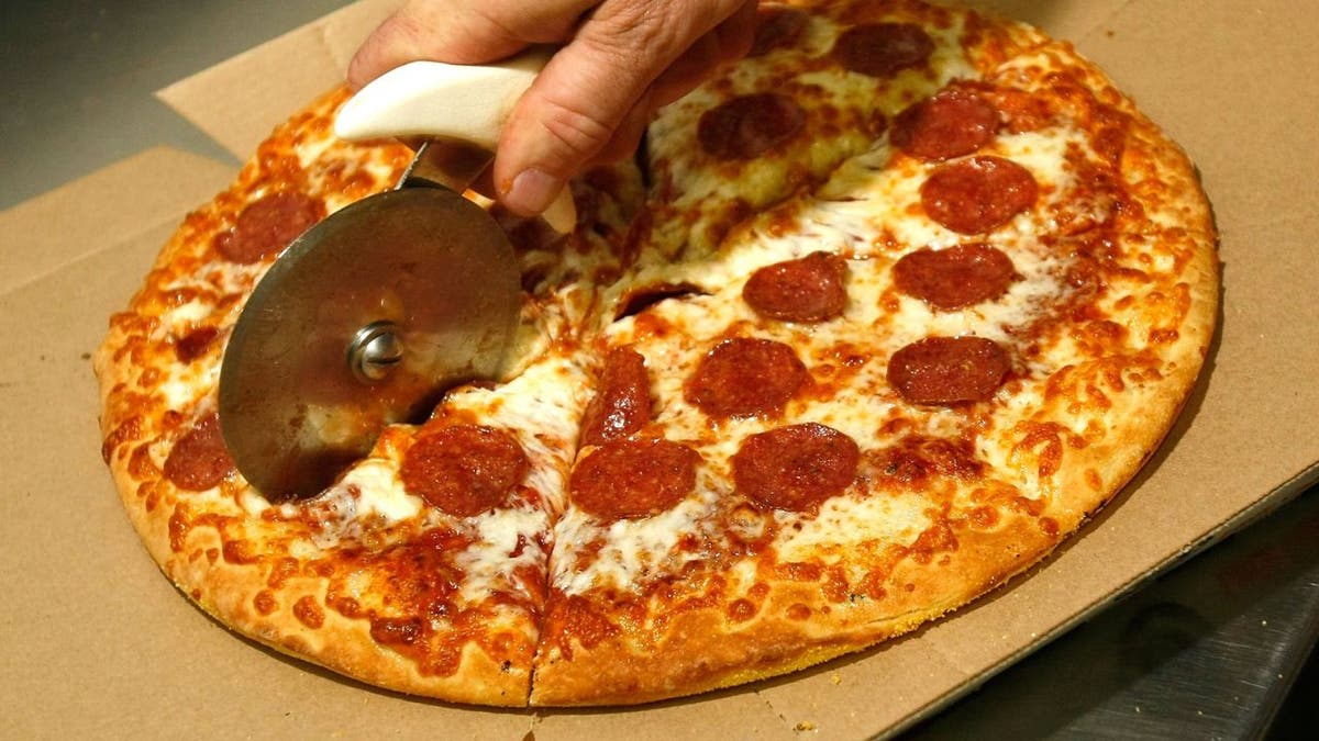 Pizza de pepperoni sendo fatiada