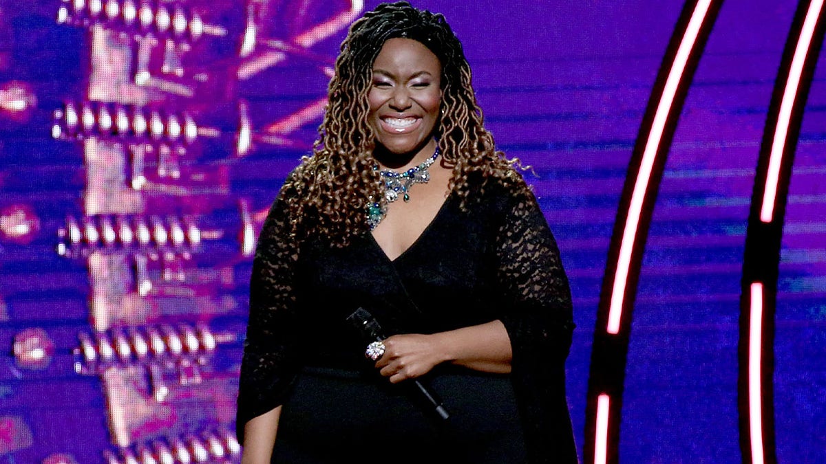 Mandisa smiling holding a microphone