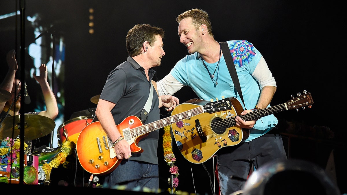 Michael J. Fox dan Chris Martin di atas panggung dengan gitar