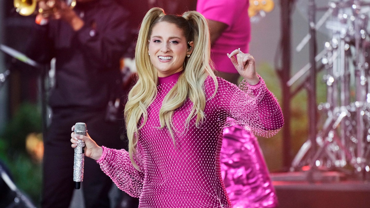 Meghan Trainor performs on NBC's Today show at Rockefeller Plaza in New York while wearing a shiny pink dress with a white mesh layer.