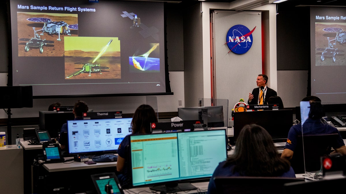 Bobby Braun gave a presentation on the Mars sample return flight system in the Perseverance Rover 2020 Mission Operations area of ​​the Jet Propulsion Laboratory, which was filled with desks and computers.