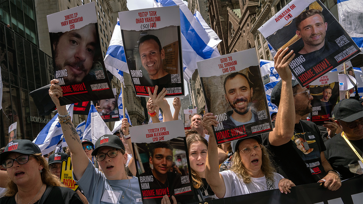 Supporters of Israel hold up signs showing the faces of some hostages taken by Hamas