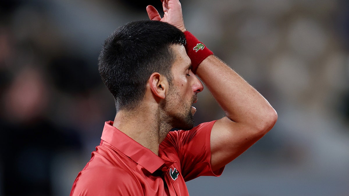 Novak Djokovic wipes forehead with hand