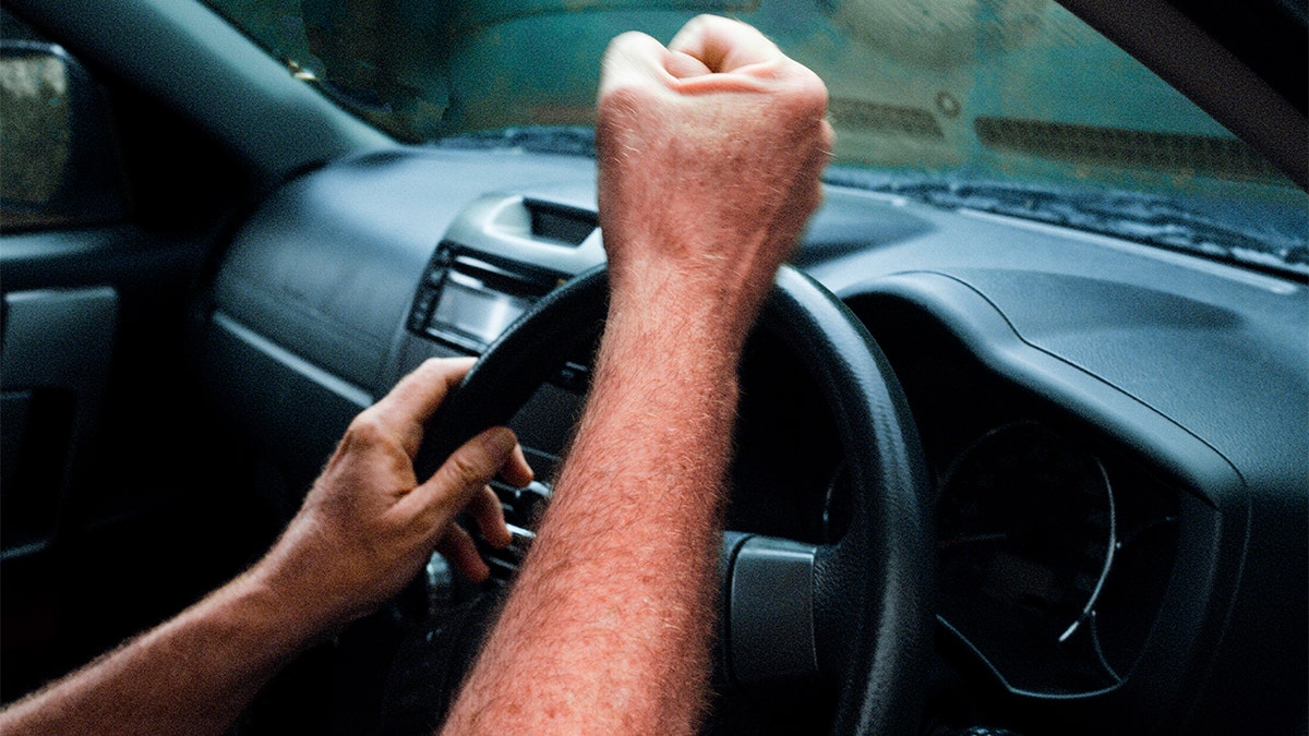 Man pounding steering wheel with fist