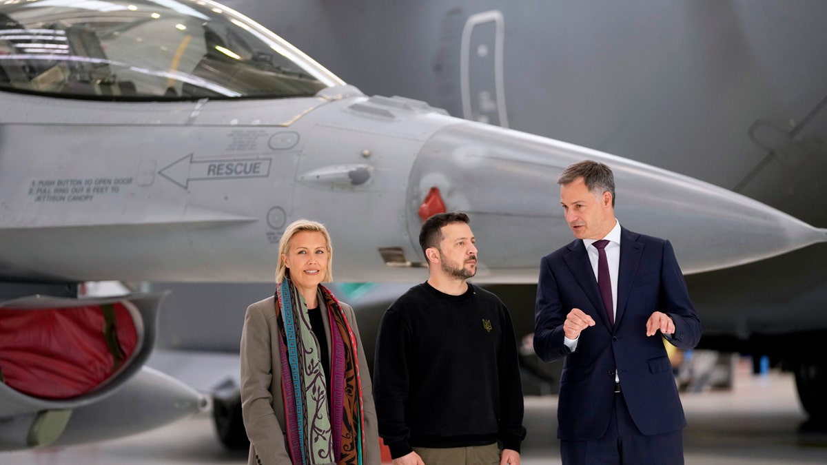 Belgium's Defense Minister Ludivine Dedonder, left, Ukraine's President Volodymyr Zelenskyy, center, and Belgium's Prime Minister Alexander De Croo, right, stand in front of an F-16 at Melsbroek military airport in Brussels, on May 28, 2024.