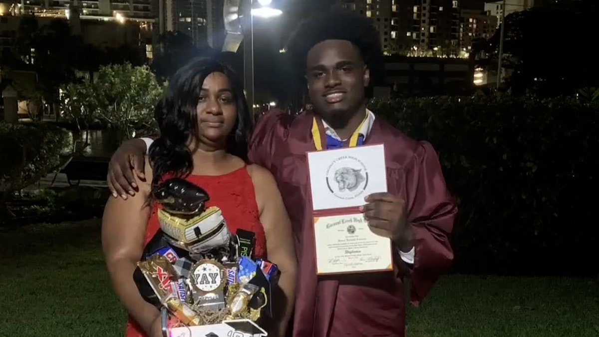 high school graduate takes photo with family