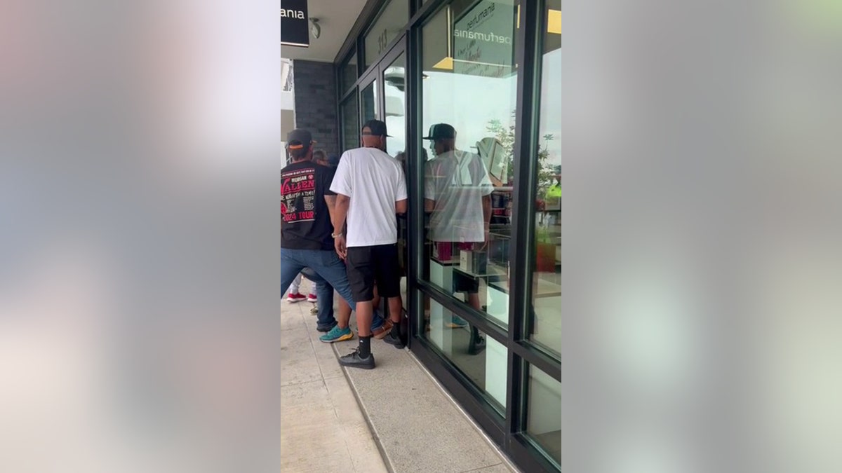 bystanders holding front door of store shut