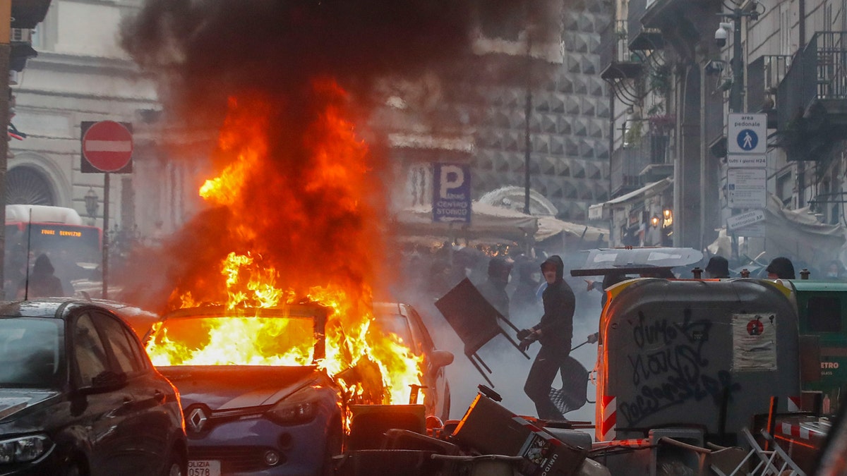 Supporters of the Eintracht Frankfurt soccer team set a police car on fire as they clash with police in Naples, Italy.