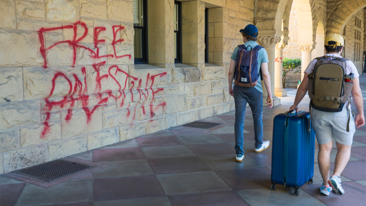 students walk with graffiti at Stanford University