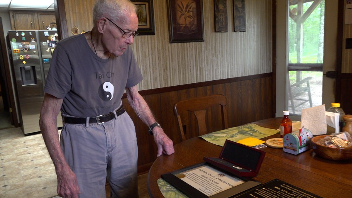 Tolley Fletcher looks at his honors given to him inside his home for his service in WWII