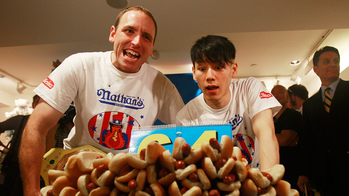 Takeru Kobayashi and Joey Chestnut in front of the hot dogs