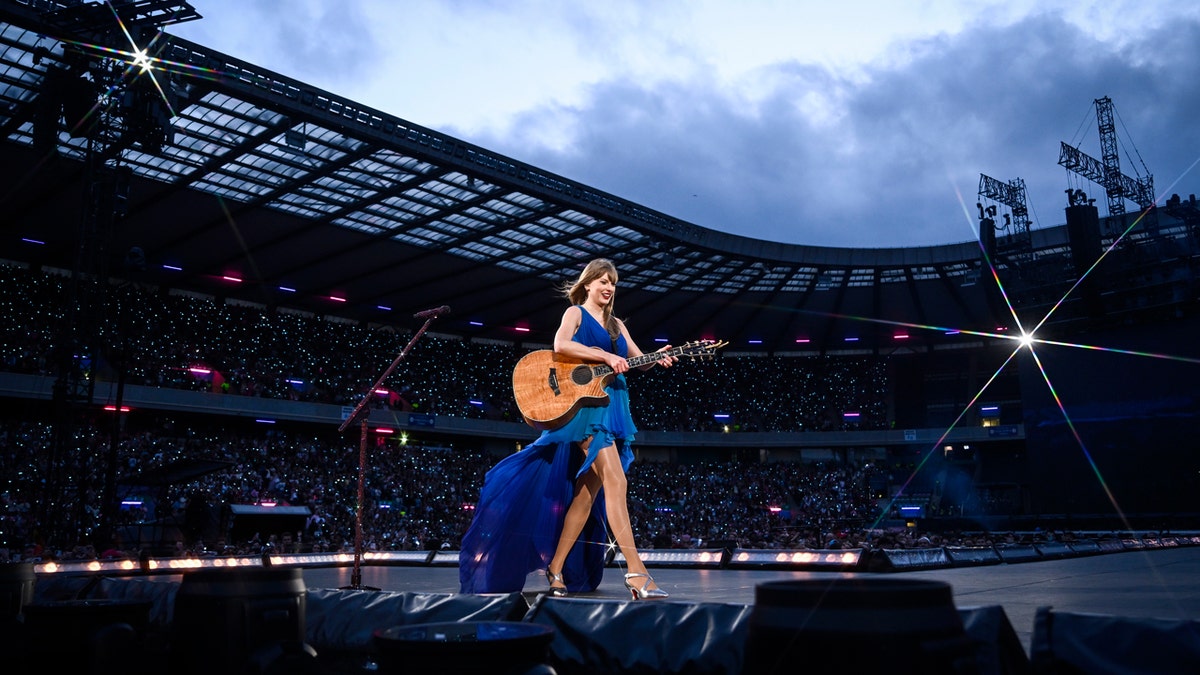 Taylor Swift carries her guitar