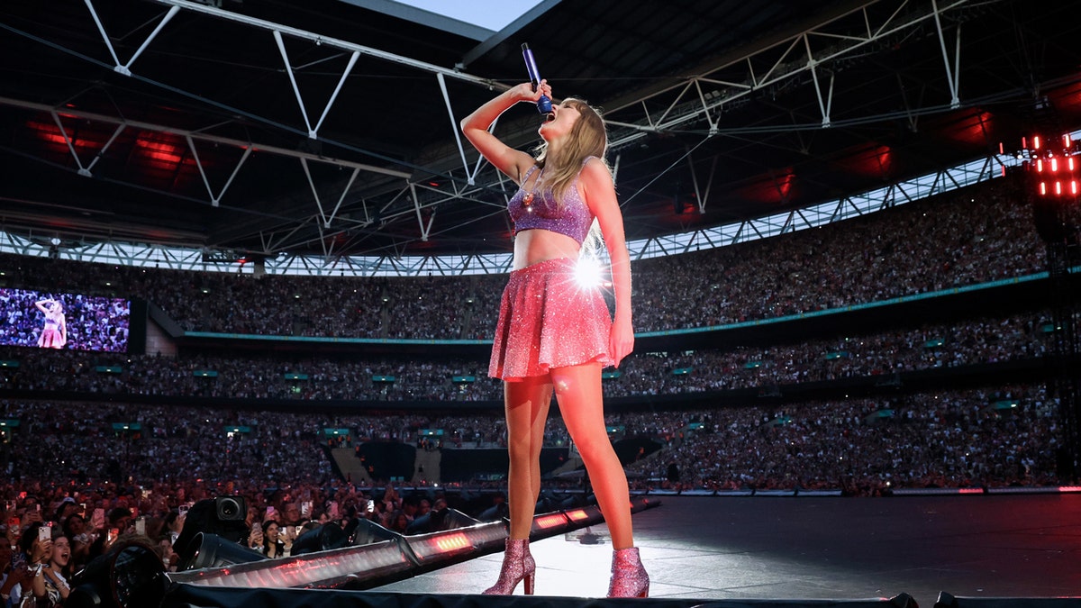 Taylor Swift usando um set rosa e roxo de 1989 durante a Eras Tour