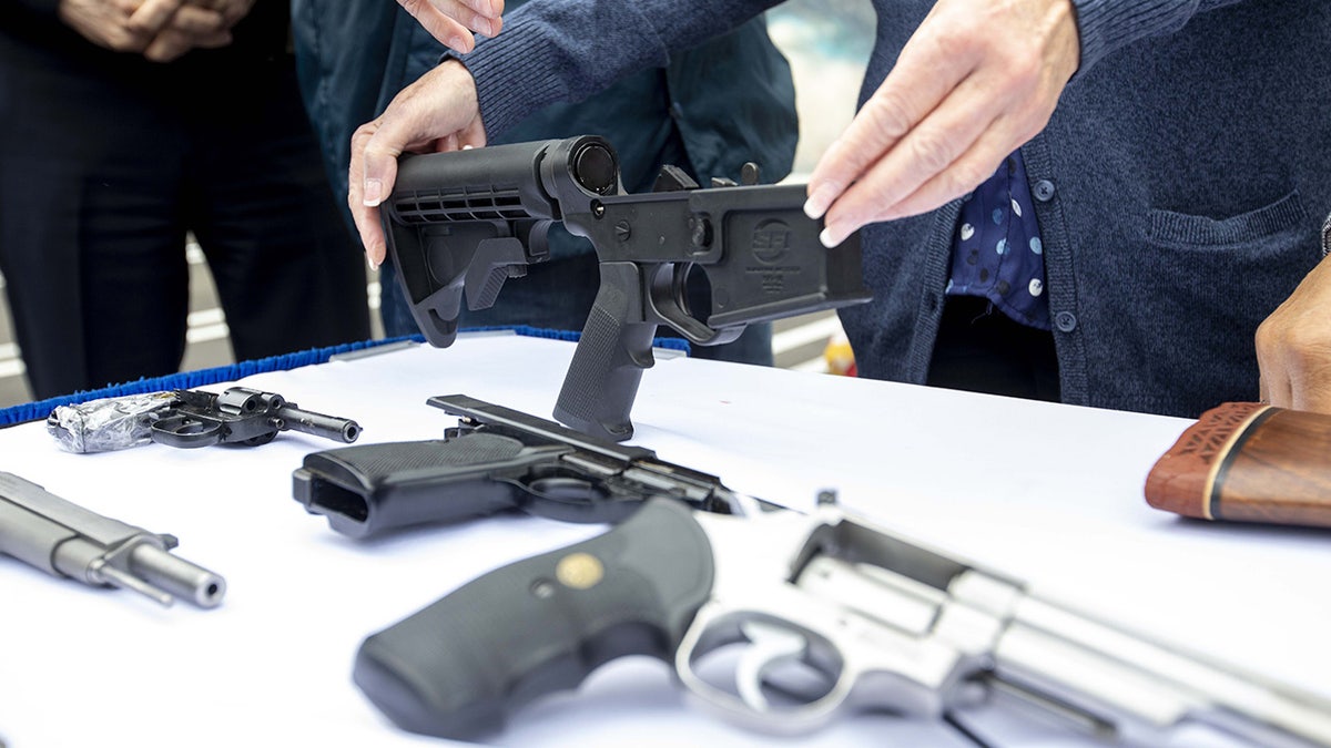 A bump stock and handguns collected during a buyback event in the Wilmington neighborhood of Los Angeles, California, on Saturday, March 4, 2023.