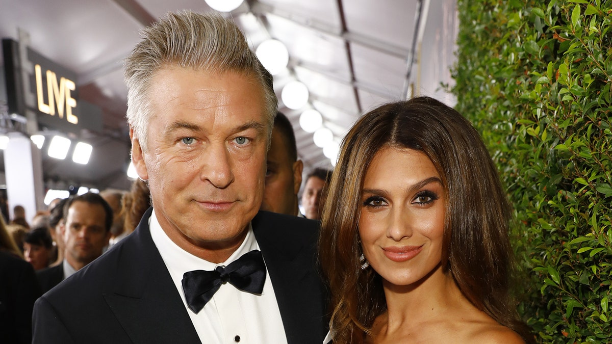 Alec Baldwin wears bow tie and black suit with wife Hilaria in floral print dress.