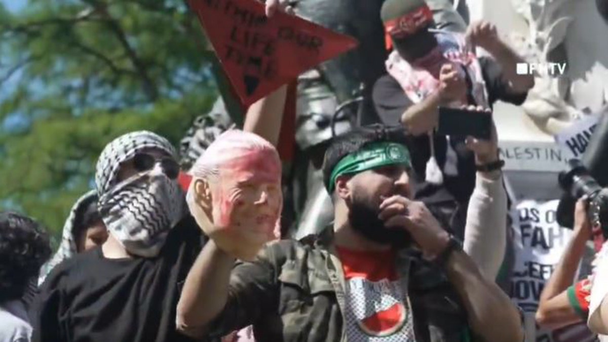 Man holding bloodied Biden mask and Hamas headband