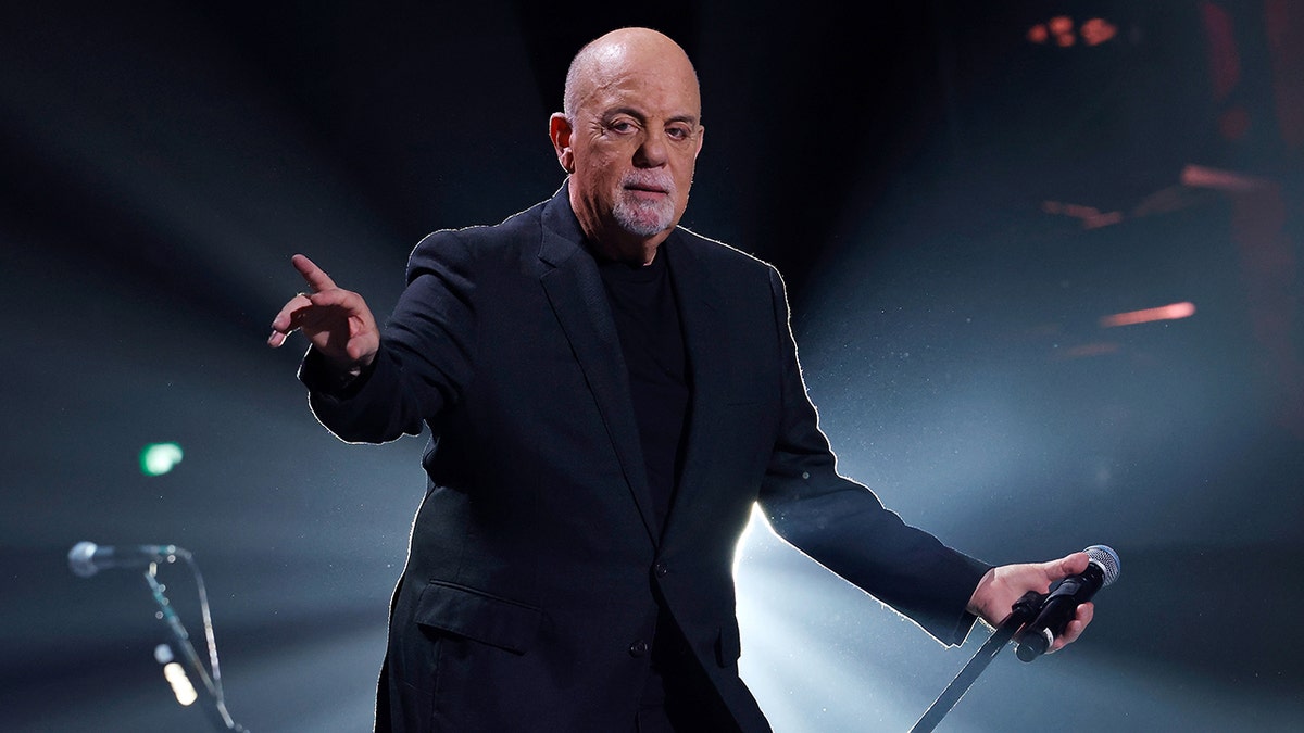 Billy Joel in a suit on stage performing