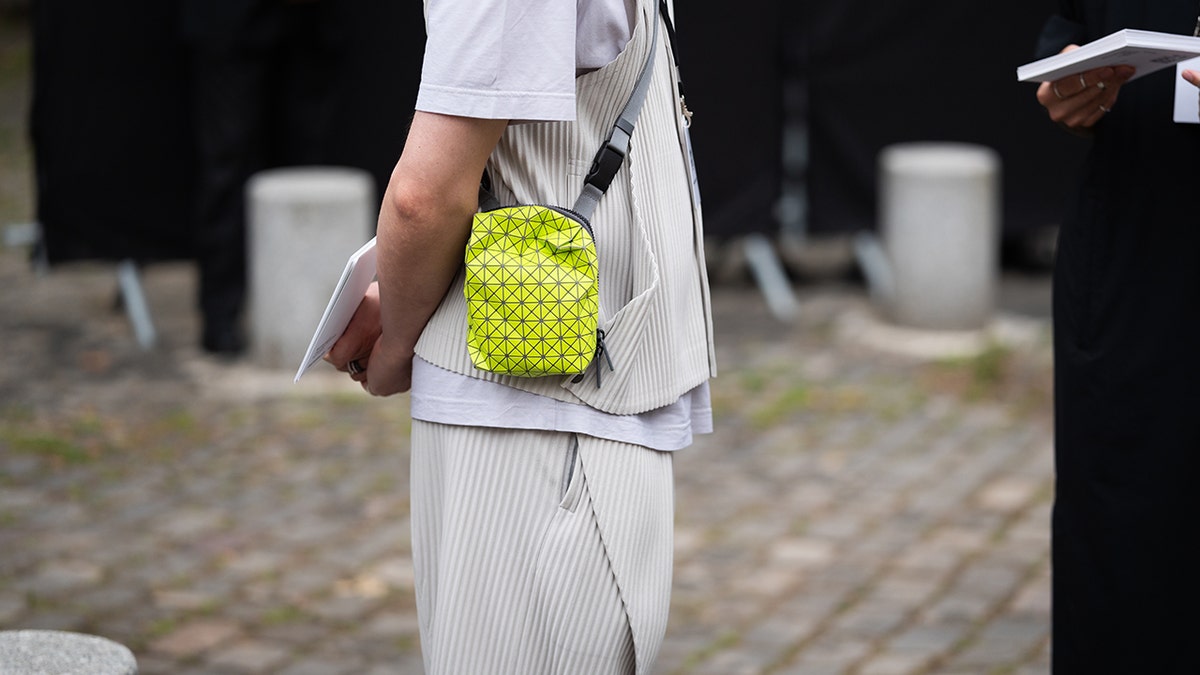 A neutral colored outfit with a bright green purse