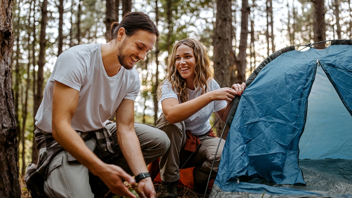 A couple setting up a tent.