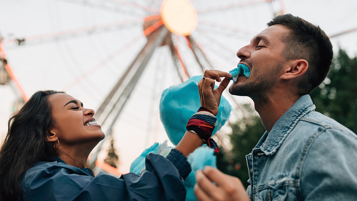 Girlfriend feeding boyfriend cotton candy