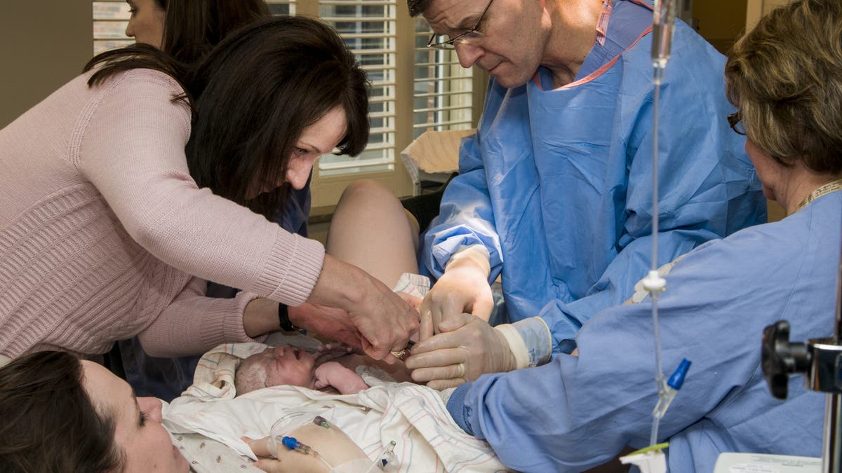 Doctor and woman cut baby's umbilical cord