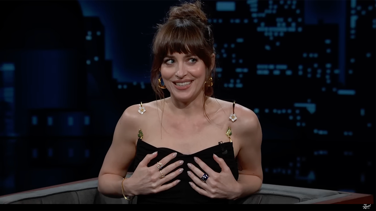 Dakota Johnson in a black dress holds her boobs on 'Jimmy Kimmel Live!'