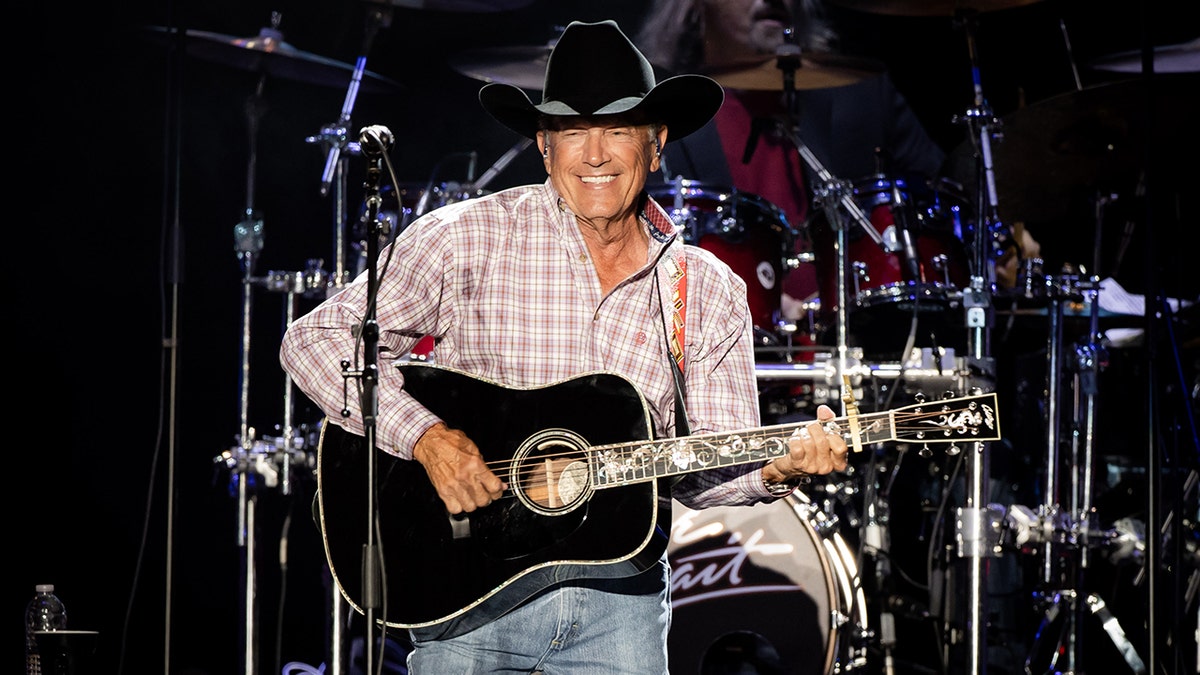 Country star George Strait strums guitar on stage.