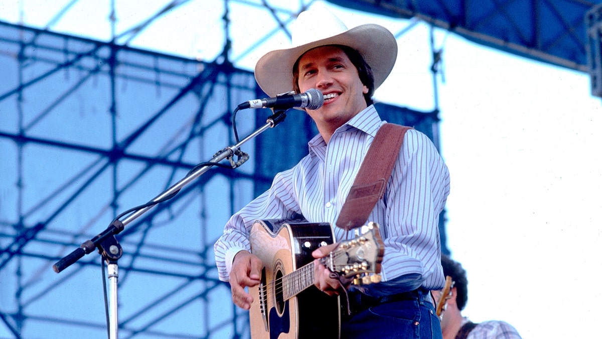 Country star George Strait plays the guitar at a concert.