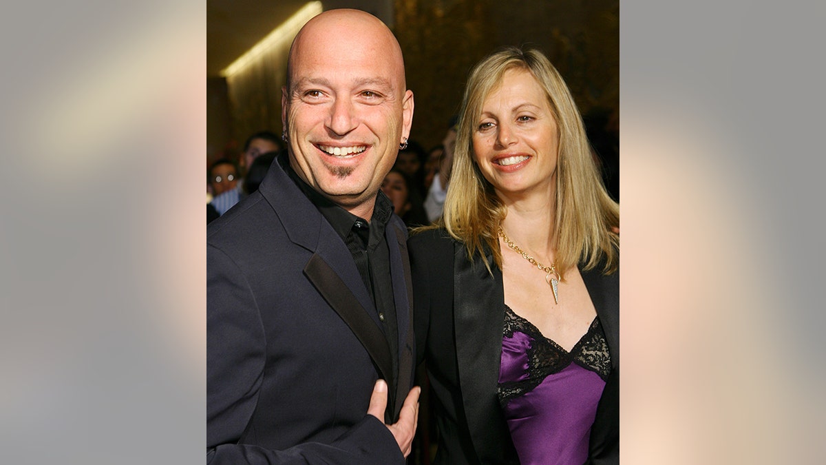 Howie Mandel in a black suit with wife Terry in a purple and black lace dress